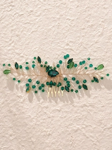 Detailed close-up of handmade gold wire hair comb with green crystals and leaf design
