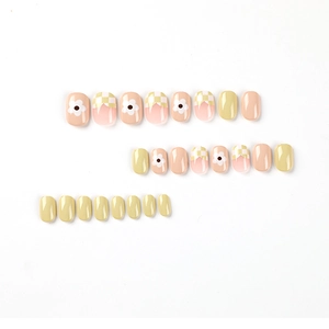 Press-on nail set with yellow daisy patterns and checkered designs on white background