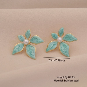 Detailed view of green flower stud earrings with pearl centers and gold steel edges