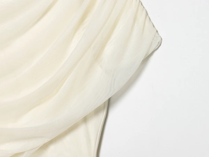 Detailed close-up of layered mesh fabric texture on an elegant cream white dress