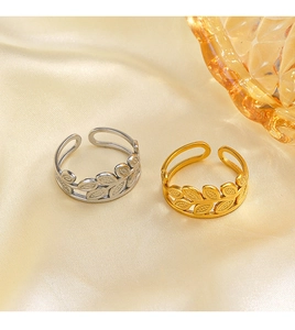 Detail shot of gold and silver leaf adjustable rings on elegant silk fabric background