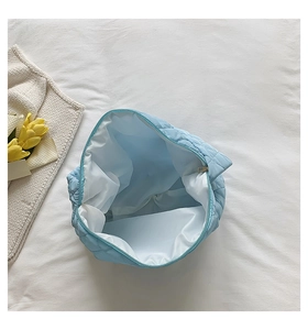 Close-up of light blue quilted makeup bag with white lining and zipper closure