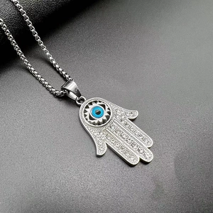 Détail de la main de Fatima avec œil bleu et strass brillants sur une chaîne à mailles