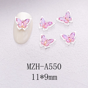 Macro detail of gradient pink crystal butterfly nail charms with silver metal frame