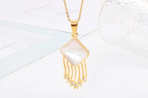 Detailed macro of golden tassel necklace with white mother-of-pearl and crystal accents