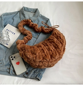 Detail of a brown quilted plush moon bag on denim jacket with lifestyle accessories