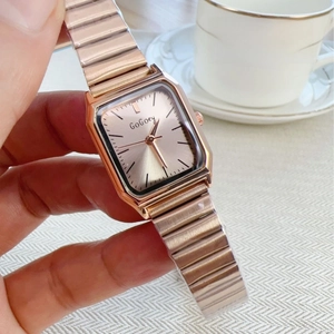 Elegant rose gold square watch with metallic strap shown in a lifestyle setting