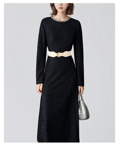 Detail of a cream leather wide waist belt with a gold circular buckle on a black dress