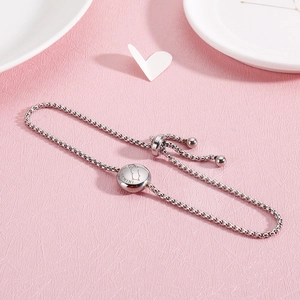 Detail of adjustable silver Gemini zodiac bracelet with crystals on pink background