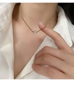 Dettaglio di una collana in titanio dorato con pendente a cuore in cristallo cangiante