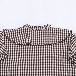 Detail of brown and white checkered fabric with layered ruffle trim and plaid pattern