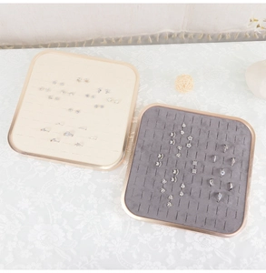 Top-down view of cream and grey jewelry display trays for rings and stud earrings