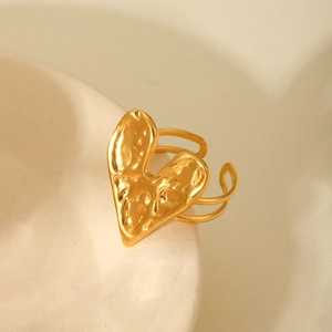 Detail of 18K gold plated heart ring with lava texture on a white ceramic surface