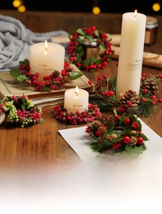 Close-up of Christmas candle ring with red berries, pine cones and warm festive decor