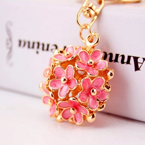 Close-up of pink enamel floral keychain with golden metal petals and lobster clasp