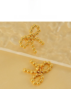 Detail of 18K gold plated bow earrings featuring a polished beaded surface design