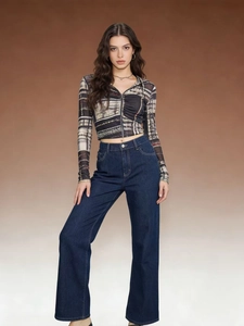 Detail of high waisted wide leg dark blue denim jeans paired with printed crop top