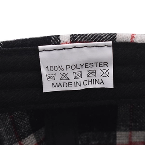 Detailansicht des Pflegeetiketts aus 100 % Polyester auf einer karierten Baseballkappe