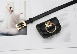 Close-up of black leather narrow belt with mini pouch and gold hardware on fashion magazine