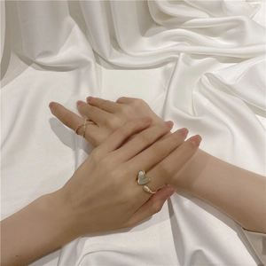 Close-up of gold rings with cross design and heart-shaped element on white silk fabric