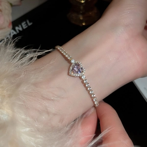 Close-up of heart-shaped pink gemstone tennis bracelet in gold finish with white zircons