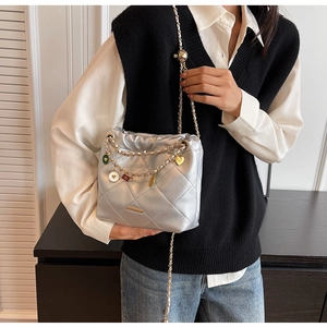 Macro detail of silver quilted bucket bag with golden heart charms and chain strap