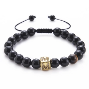 Detail of beaded bracelet featuring a gold letter M charm and tiger eye stone