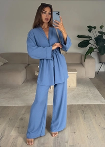 Mirror selfie showing a blue long-sleeve wrap top and wide-leg pants set in a living room
