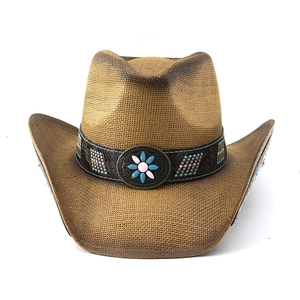 Detail of western straw cowboy hat with embossed leather band and floral metal buckle
