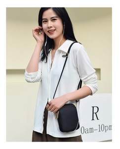Close-up of a black vertical crossbody phone bag with gold zippers and slim strap