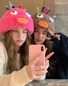 Close-up of plush funny beanies with 3D eyes and duck bills in rose and brown colors