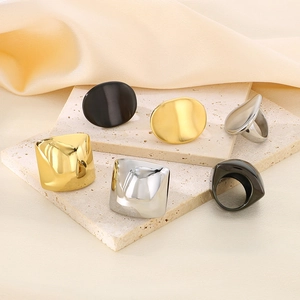 Minimalist geometric chunky rings set in gold, silver, and matte black on stone