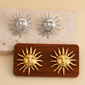 Elegant sun face earrings set in gold and silver finish on textured display blocks