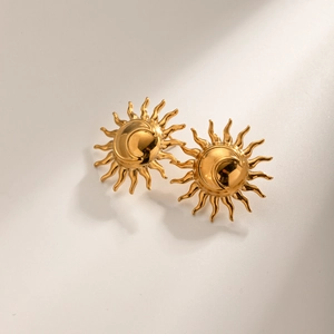 Détail macro de boucles d'oreilles soleil et lune plaquées or 18 carats sur beige