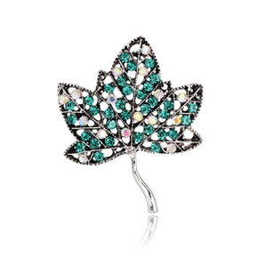 Detailed macro view of a silver maple leaf brooch with green and AB rhinestones