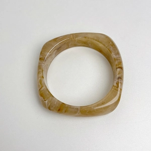 Macro shot of irregular square resin bracelet featuring a translucent amber marble pattern