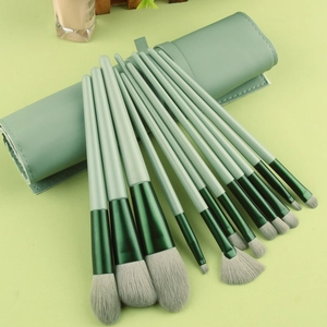 Close-up of 13-piece sage green makeup brush set with matching leather roll-up case