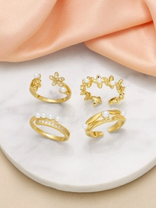 Detail view of 4-piece gold open ring set with elegant pearls and floral designs