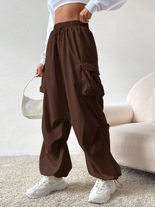 Detail view of dark brown cargo pants featuring drawstring waist and large side flap pockets