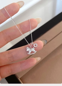 Detail of silver rocking horse necklace with mother of pearl inlay and zircon accents