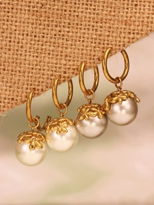 Detailed close-up of golden flower petal caps and round pearls on stainless steel earrings