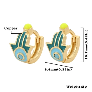 Macro shot of Hamsa hand and Evil Eye copper earrings with blue enamel and gold finish