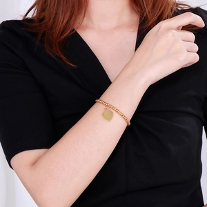 Close-up of 18k gold plated beaded bracelet with heart pendant on woman's wrist