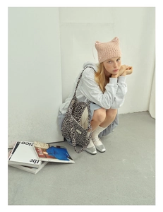 Detail of pink cat-ear knit hat with bow and leopard print tote bag for winter