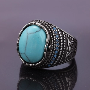 Dettaglio macro di anello in acciaio da uomo stile retrò con turchese ovale e incisioni