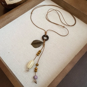 Detail of vintage necklace featuring wood beads, brass leaves and ceramic pendants
