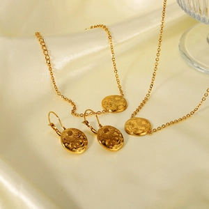 Detailed view of 18K gold plated sun and moon pendant necklace set on soft silk fabric