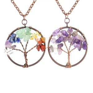 Macro detail of copper Tree of Life pendants with amethyst and chakra stones on white background