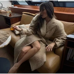 Elegant beige wool blend long coat with metal buckle belt shown in a luxury interior