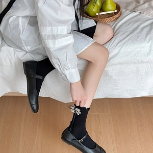 Detail of black crew socks featuring delicate white lace bow and ribbed knit texture